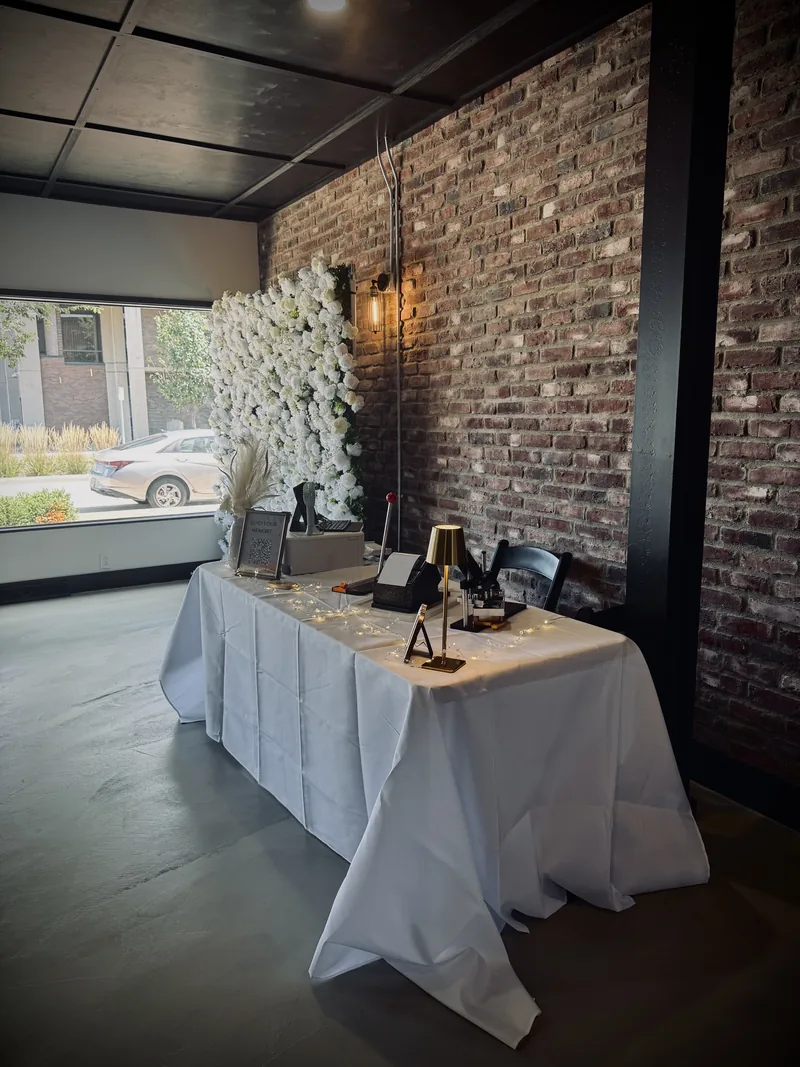 Darling Wesley Designs vendor table arranged with keepsakes and neutral floral decor in a brick-walled venue